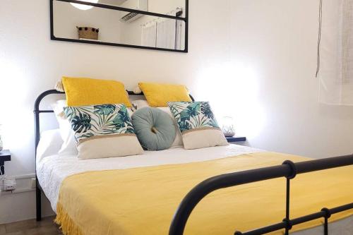 a bedroom with a bed with yellow and blue pillows at Maison dans le quartier historique de St Laurent Résidence Colibri in Saint-Laurent du Maroni