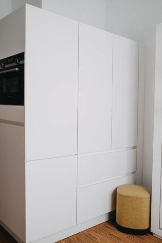 a kitchen with white cabinets and a stool at Maximilian Studios in Speyer