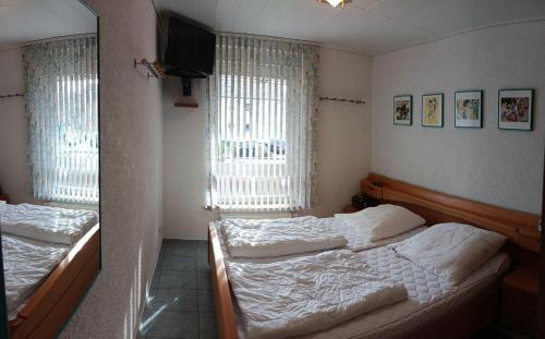 a bedroom with two beds and a television and two windows at BUPA06107-FeWo-Passat-soess in Burg auf Fehmarn