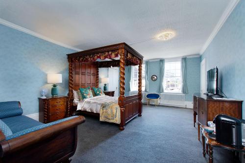 a bedroom with a canopy bed and a television at Stone Court House in Maidstone