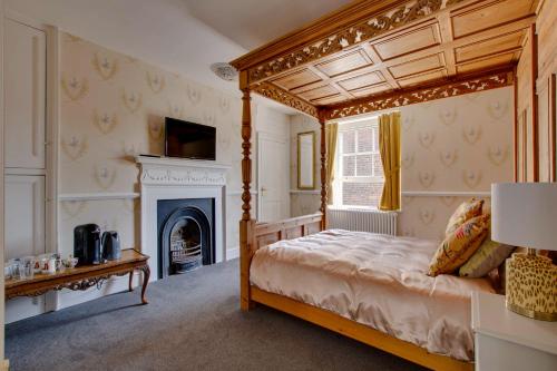 a bedroom with a canopy bed and a fireplace at Stone Court House in Maidstone