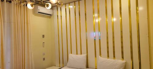 Lemmy's Villa - Private vacation home في أكوري: غرفة نوم بجدران مخططة صفراء وبيضاء ومخدات بيضاء