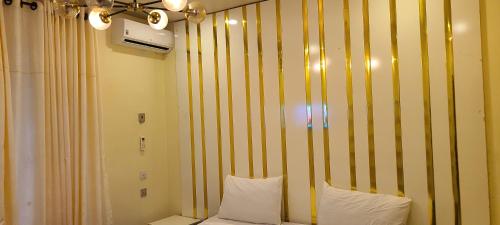 a bedroom with yellow and white striped walls and white pillows at Modern & Cheerful 2 Bedroom Villa, Alagbaka in Akure