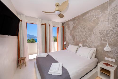 a bedroom with a bed with a ceiling fan at KLIMA BAY Beachfront Boutique Houses in Klima