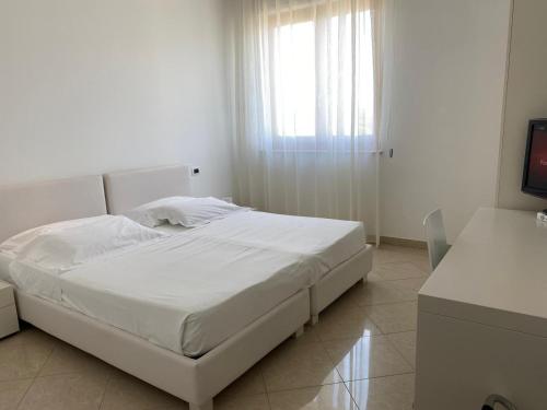 a white bed in a white room with a window at Pietre Nere Resort & Spa in Modica