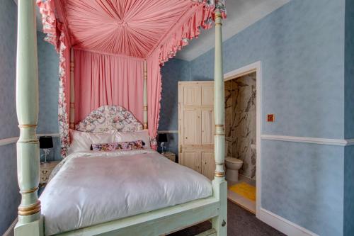 a bedroom with a canopy bed with pink curtains at Stone Court House in Maidstone