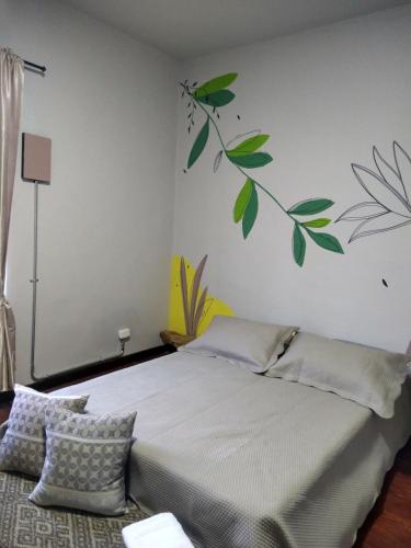 1 dormitorio con 1 cama con una rama en la pared en Casa la 15 Pereira, en Pereira