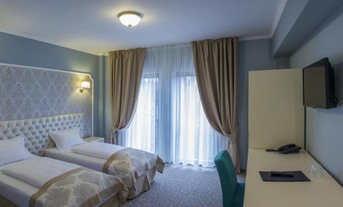um quarto de hotel com duas camas e uma secretária em Hotel Bulevard em Hunedoara