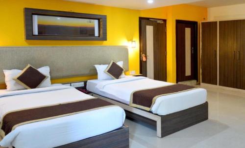 2 camas en una habitación de hotel con paredes amarillas en DIDI Hotel Alambagh, en Lucknow