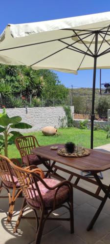 a wooden table and chairs under an umbrella at Το Πατρικό - To Patriko Epidavros in Ancient Epidavros