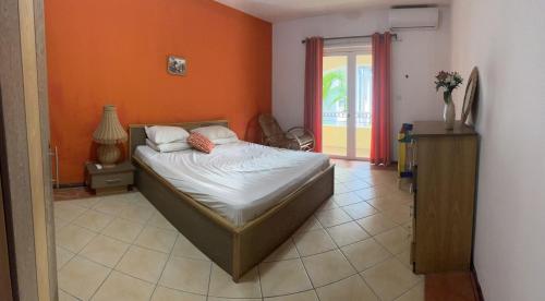 a bedroom with a bed and an orange wall at A’s Beach Apartment in Flic-en-Flac