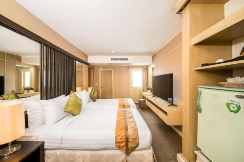una camera d'albergo con letto e TV di Niran Grand Hotel a Bangkok