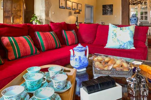 a living room with a red couch with blue and white china at Maison Manechal in Monfaucon