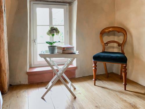 a chair sitting next to a table with a window at Maison Manechal in Monfaucon