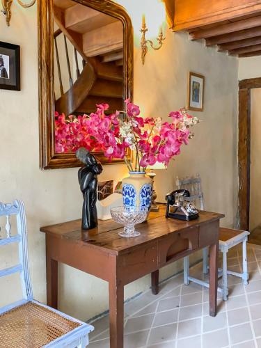 a vase of flowers on a table with a mirror at Maison Manechal in Monfaucon