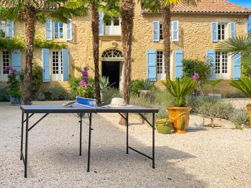 a table in front of a building with palm trees at Maison Manechal in Monfaucon