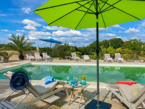 a pool with two chairs and a green umbrella at Maison Manechal in Monfaucon