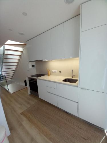 een keuken met witte kasten, een wastafel en een trap bij Casa Aveiro Modern House in Aveiro
