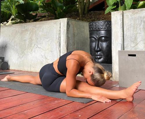 una mujer tendida en una esterilla de yoga con una estatua en Hostel-Island Paradise, Saboga Lodge and Villa Noelia, en Panamá