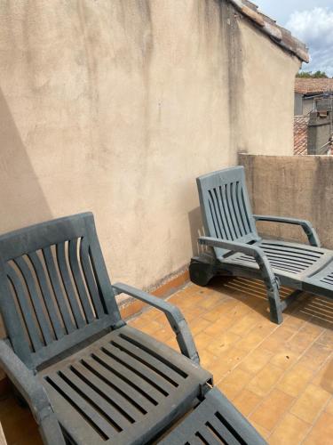 two chairs sitting on a deck next to a wall at Rooftop vue cité médiévale ! in Carcassonne