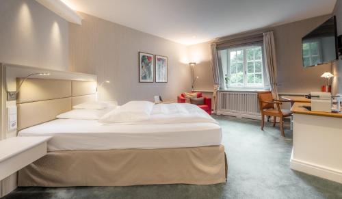 a hotel room with a large bed and a desk at Waldhaus Reinbek in Reinbek