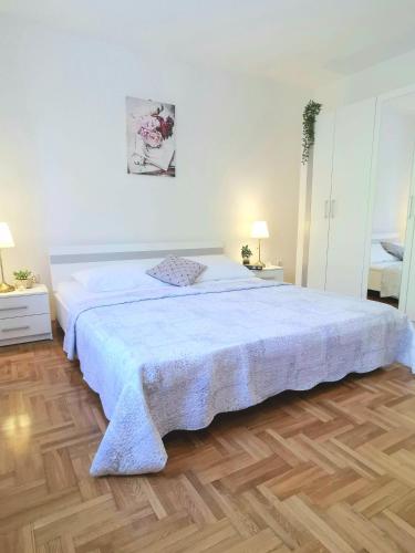 a large white bed in a bedroom with a wooden floor at Apartment Olivia in Šmrika