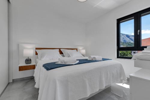 ein weißes Schlafzimmer mit einem weißen Bett und einem Fenster in der Unterkunft Apartment Nizza in Makarska
