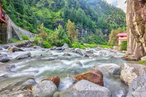 a river in the mountains with rocks at Baan by Snow City Farm in Vashisht