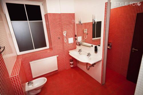 a red tiled bathroom with a sink and a toilet at Hotel Slovan in Lučenec