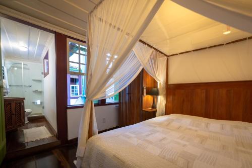 a bedroom with a canopy bed and a window at Casa Duas Suítes no Centro Histórico in Paraty