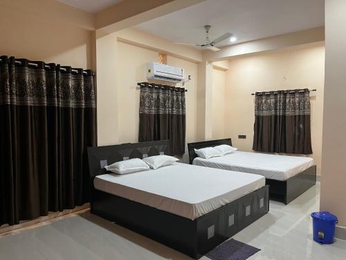 two beds in a room with black curtains at Hotel Krishna Paradise in Deoghar
