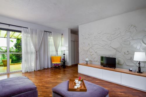 a living room with a couch and a tv at Ewange - A Casa Mia in Kampala