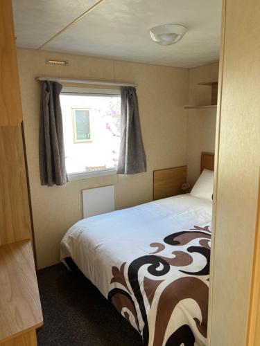 a small bedroom with a bed and a window at Chris’s caravan in Abergele