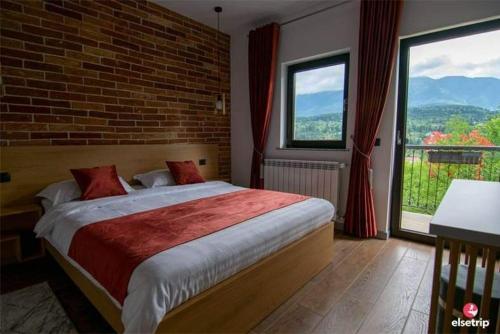 - une chambre avec un grand lit et un mur en briques dans l'établissement Liniștea Codrului, à Borşa
