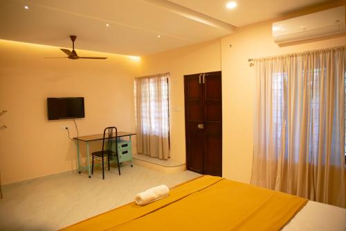 a bedroom with a bed and a desk and a television at Marari Edens in Mararikulam