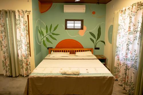 a bedroom with a bed with a painting on the wall at Marari Edens in Mararikulam