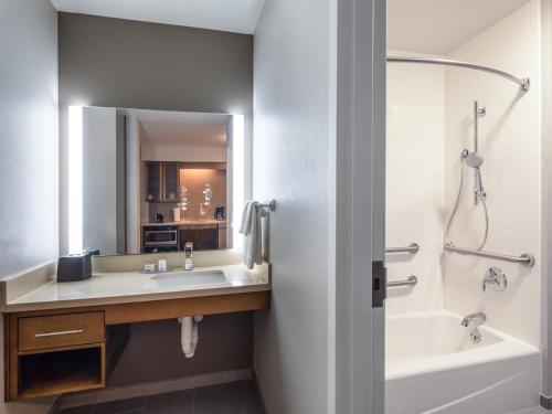 a bathroom with a sink and a tub and a mirror at Staybridge Suites - Sioux City Southeast by IHG in Sioux City