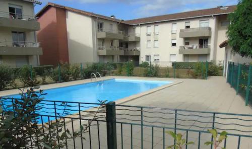 a swimming pool in front of some apartment buildings at 2 Bedrooms Confortable Wifi FIBRE ALL EQUIPMENT Provided Near Airbus Alten Expleo Thales Sopra in Toulouse