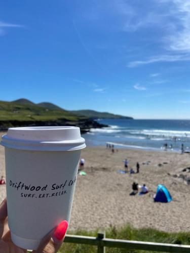 a hand holding a cup of coffee at the beach at Chapel Cross House in Ballinskelligs