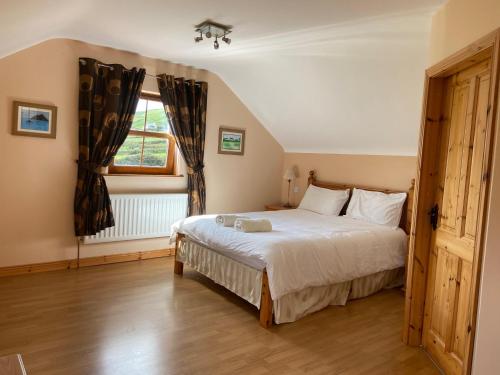 a bedroom with a large bed and a window at Chapel Cross House in Ballinskelligs