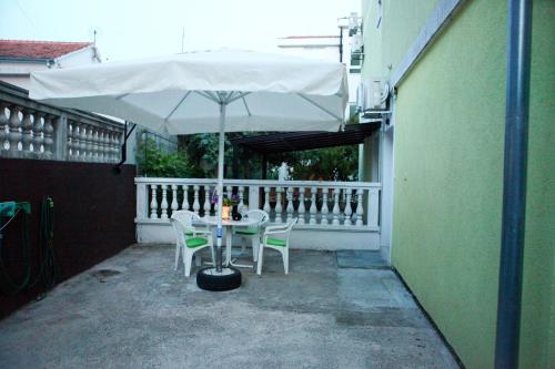 a table and chairs under an umbrella on a balcony at Apartmani Andrej Vodice in Vodice