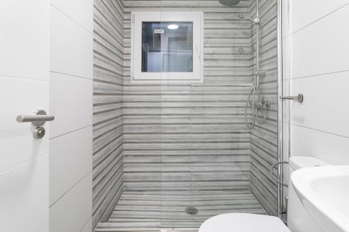 uma casa de banho com um chuveiro, um WC e uma janela. em Apartamento El Mar 2 em Alicante