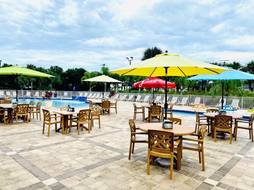 a group of tables and chairs with umbrellas next to a pool at Ocean Grove RV Resort St Augustine in Saint Augustine