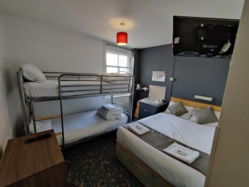 ブラックプールにあるBlarney Stone Hotelの二段ベッド2台、テレビが備わる小さな客室です。