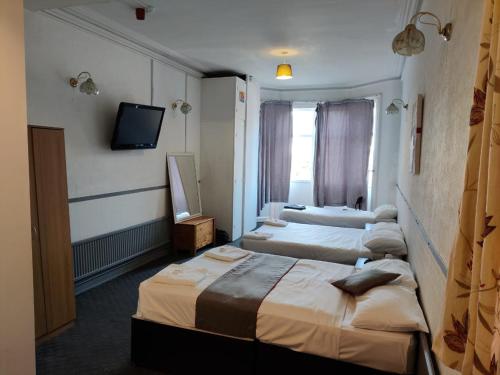 ブラックプールにあるBlarney Stone Hotelのベッド3台とテレビが備わるホテルルームです。