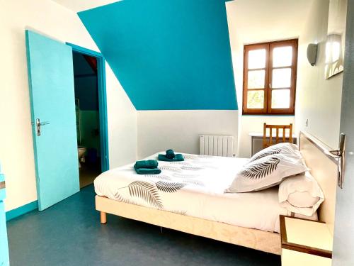 a bedroom with a bed with a blue accent wall at Auberge Le Beaulieu -Cantal in Beaulieu