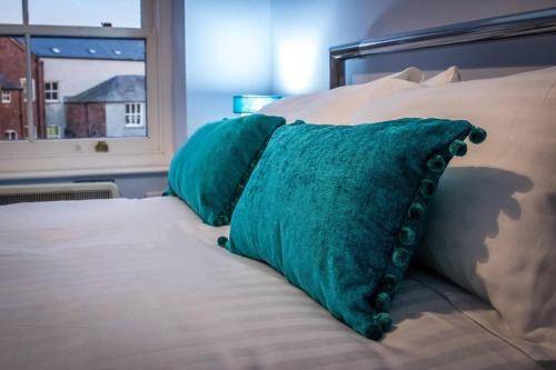 zwei grüne Kissen auf einem Bett mit Fenster in der Unterkunft Beautiful 1-Bed Apartment in central Ulverston in Ulverston