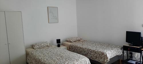 een kamer met 2 bedden en een tv. bij Casa da Fonte Velha - Covilhã in Covilhã