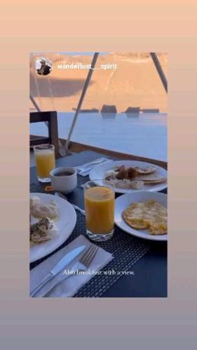 a table with plates of food and glasses of orange juice at Harmony Luxury Camp in Wadi Rum