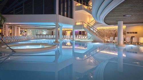 a swimming pool in a building with a spa at Sanadome Hotel & Spa Nijmegen in Nijmegen